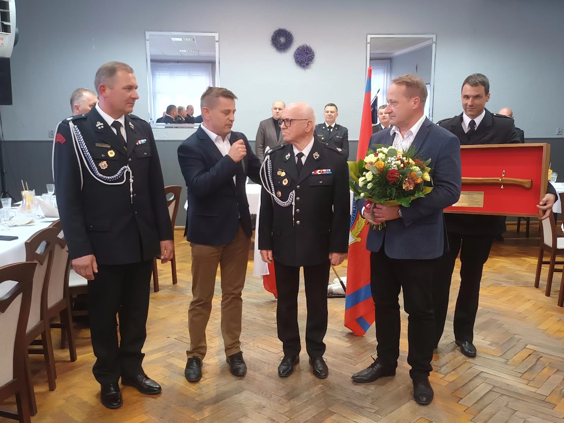 Strażacy oraz Przewodniczący Rady i Burmistrz z kwiatami